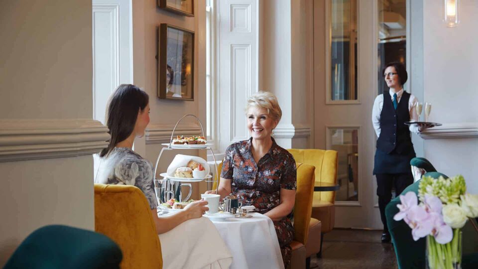 Guests enjoying a delightful afternoon tea in an elegant hotel lounge with plush seating and attentive service.