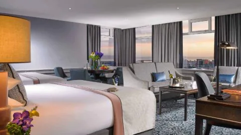 Elegant hotel room with sea view, luxurious bedding, cosy seating area, and ambient lighting for a relaxing stay.