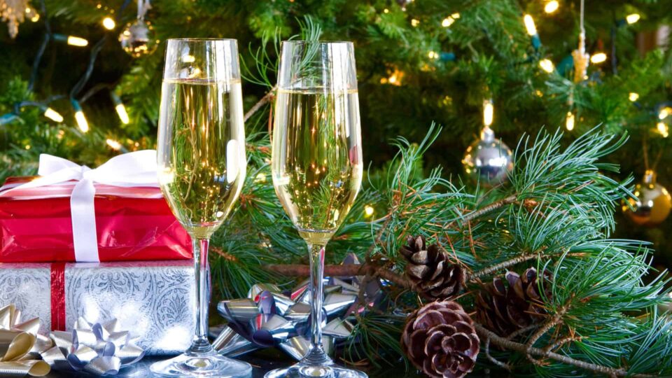 Two,Glasses,Of,Champagne,On,Green,Christmas,Background,And,Gifts