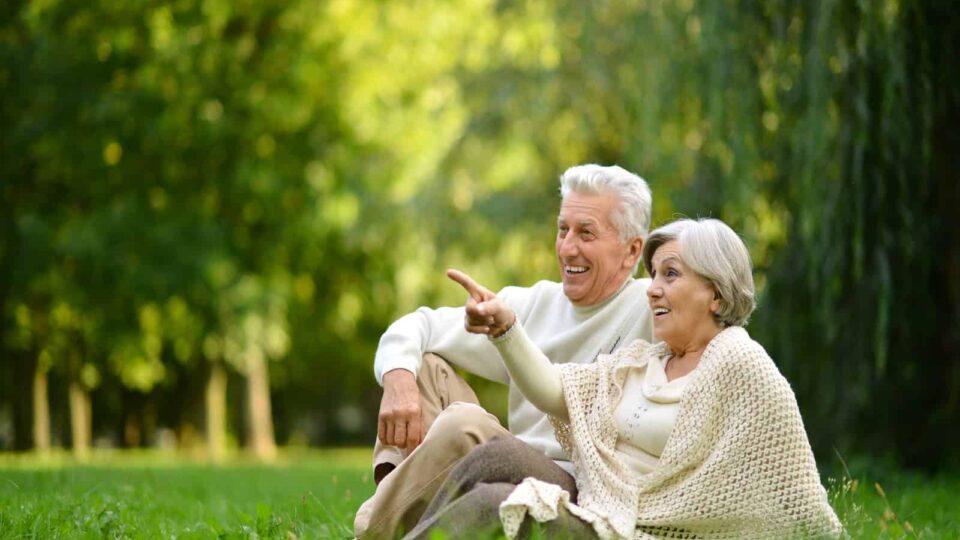 Elderly couple enjoying a peaceful moment in lush green park, perfect for relaxation and nature strolls.