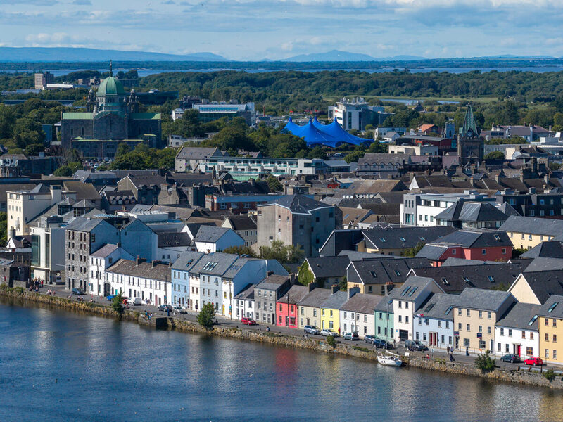 Charming riverside view with colourful houses and lush greenery, offering a serene, picturesque setting for a perfect stay.