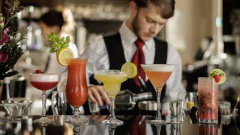 Guests enjoy vibrant cocktails at a stylish bar with expert service, elegant glassware, and fresh garnishes.