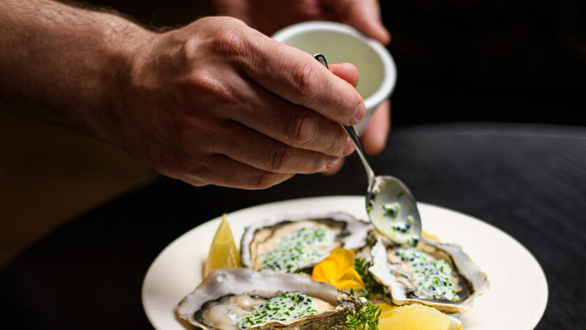 Fresh oysters garnished with herbs and lemon on ice at a fine dining restaurant, offering a luxurious culinary experience.
