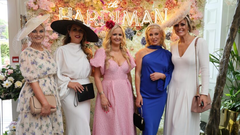 Elegant guests in stylish dresses enjoy a floral-decorated hotel event area, exuding a welcoming and luxurious ambience.