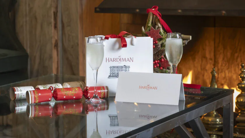 Cosy hotel lounge with festive decor, champagne glasses, and a welcoming fireplace, ideal for a relaxing stay.