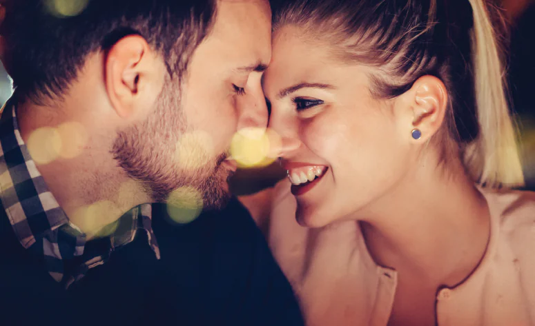 Romantic couple smiling at dinner in elegant hotel restaurant with warm lighting, perfect for a memorable getaway.