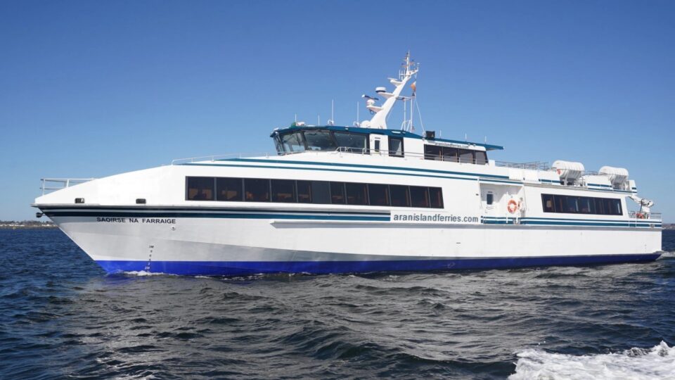 Modern ferry cruising on calm blue sea under clear sky, offering scenic coastal views and a relaxing maritime journey.