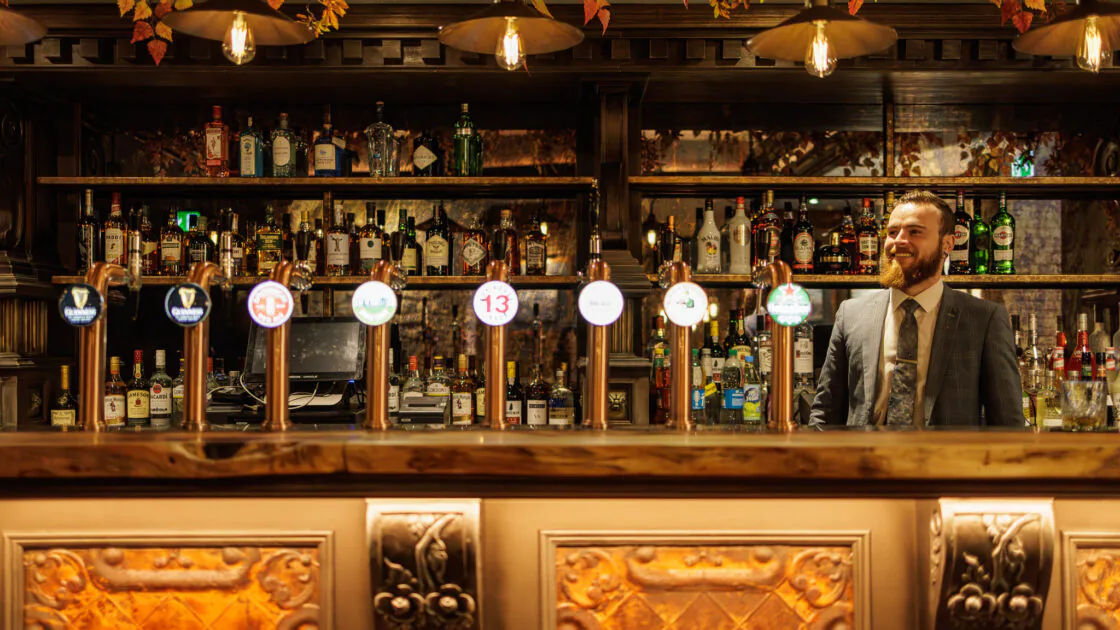 Cosy hotel bar with a friendly bartender, elegant wood panelling, autumn decor, and a wide selection of spirits.