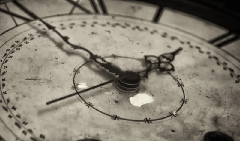 Close-up of an old, worn clock face with Roman numerals and ornate hands showing the time as 9:15.