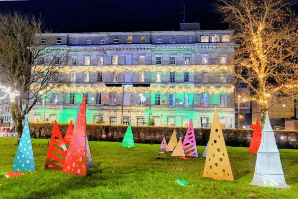 A building with lights and trees in front of it.
