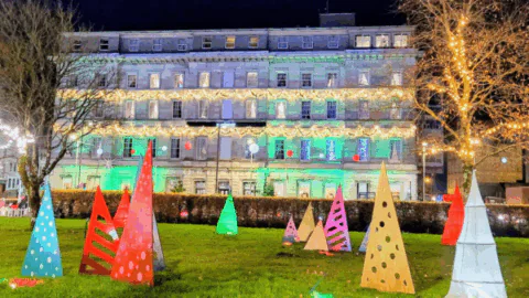 A building with lights and trees in front of it.