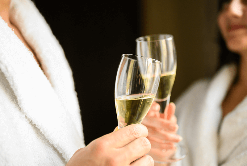 Guests in plush robes enjoy champagne, evoking luxury and comfort at the hotel spa.
