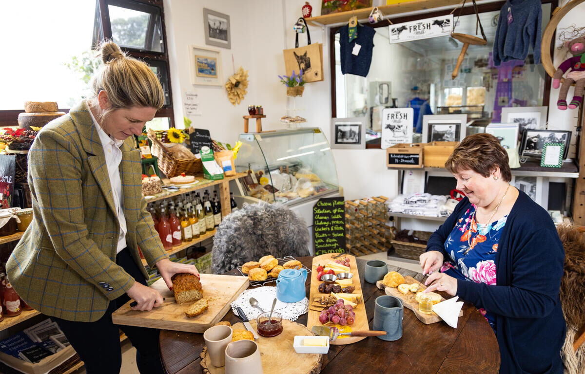 Guests enjoying homemade bread and local produce in cosy hotel shop with fresh bakery items and local crafts displayed.