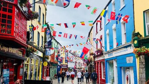 Vibrant street view with colourful buildings and international flags, offering lively shops and dining in a charming, festive atmosphere.